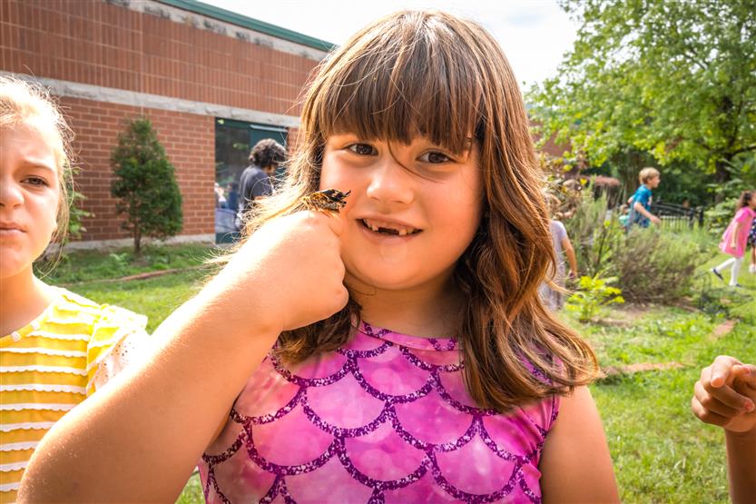 A girl smiles while holding a butterfly